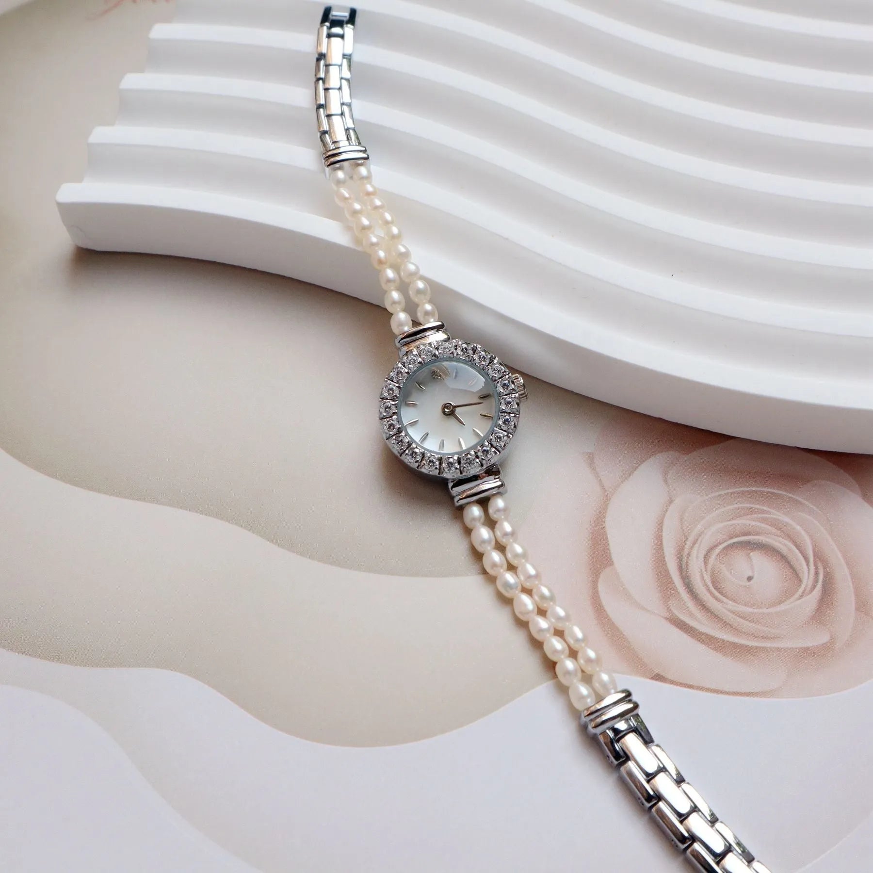 Women's light gold bracelet watch with freshwater pearls and a small round dial.