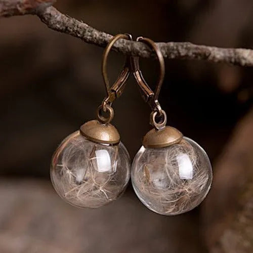Transparent glass ball earrings with a dandelion seed inside, on a silver French hook.