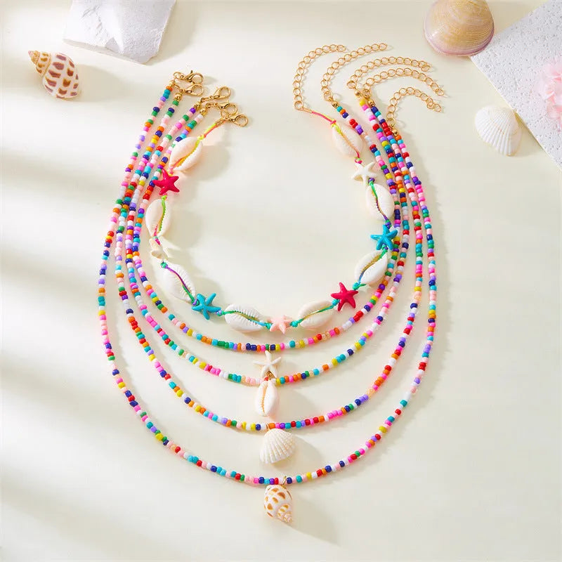 Five women's fashion necklaces with starfish and shell bead designs in blue and multicolour options