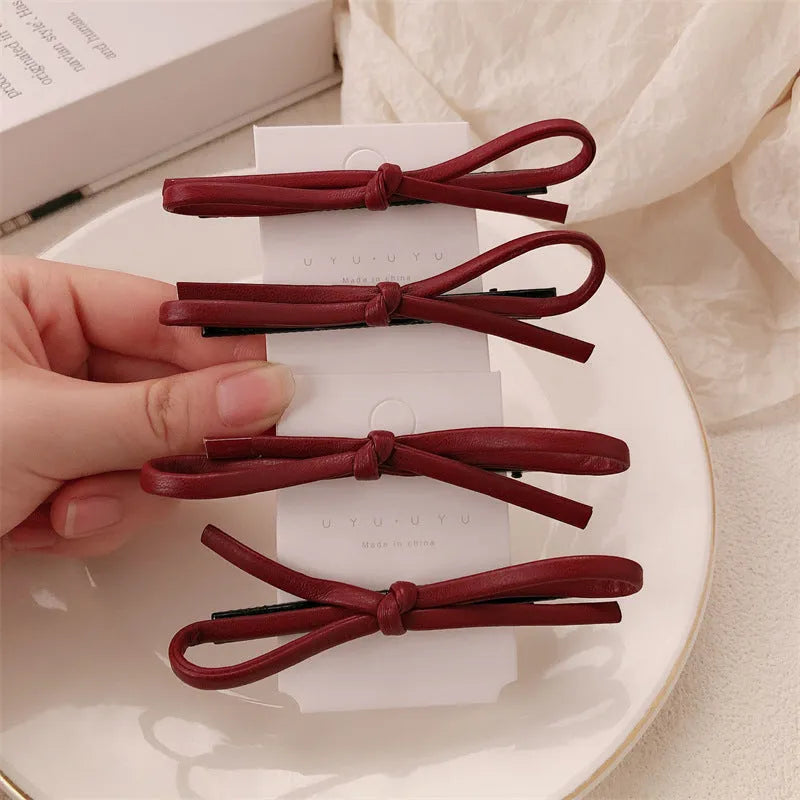 Wine red leather bow design hair barrettes on a white background.
