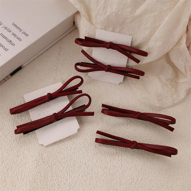 Wine red leather bow design hair barrettes on a white background.