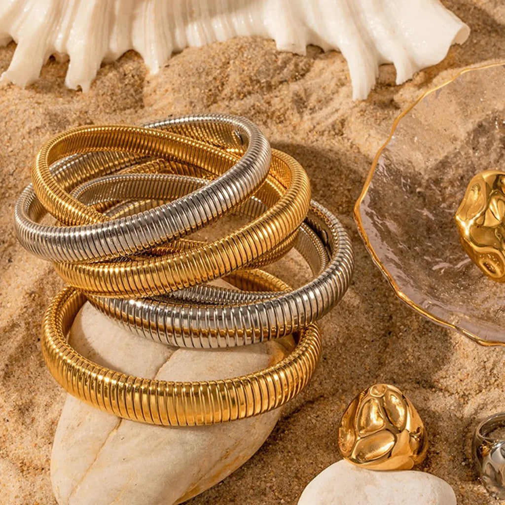 Women's titanium steel bracelet with vertical stripes, shown in gold and silver colours with ring elastic closure.