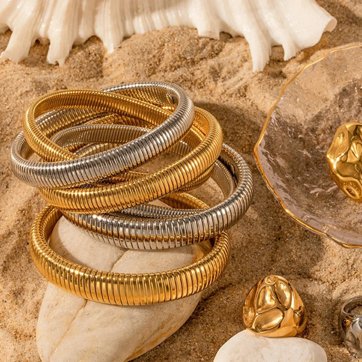 Women's titanium steel bracelet with vertical stripes, shown in gold and silver colours with ring elastic closure.