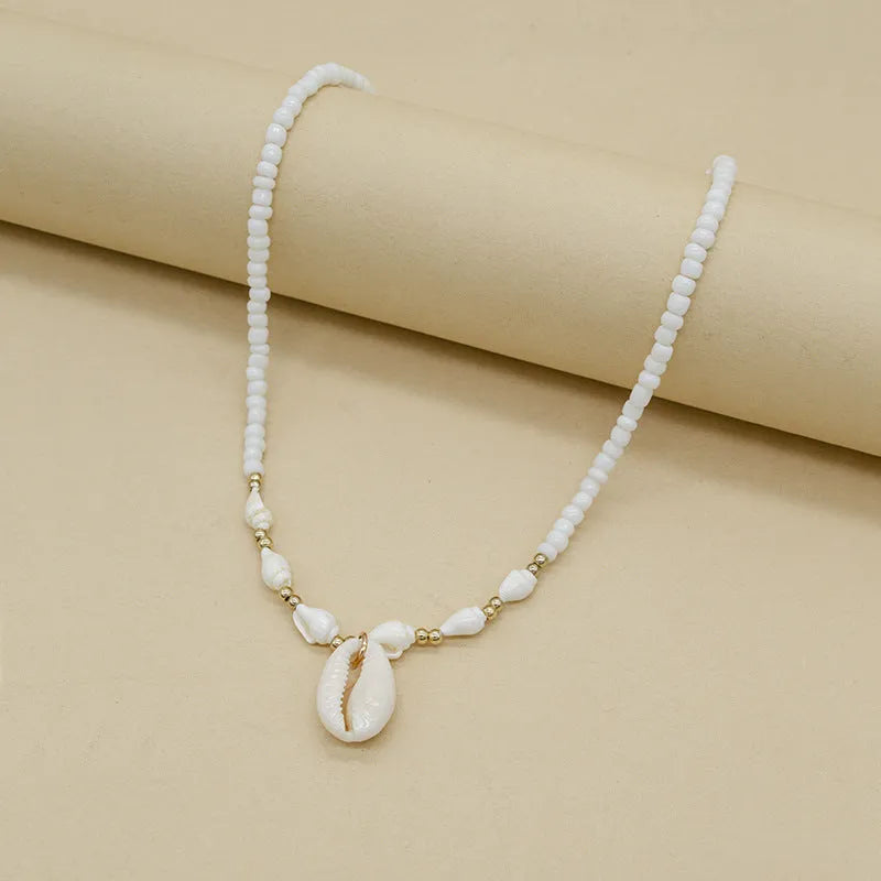 White bead necklace with a mother of pearl conch shell pendant on a regular chain.