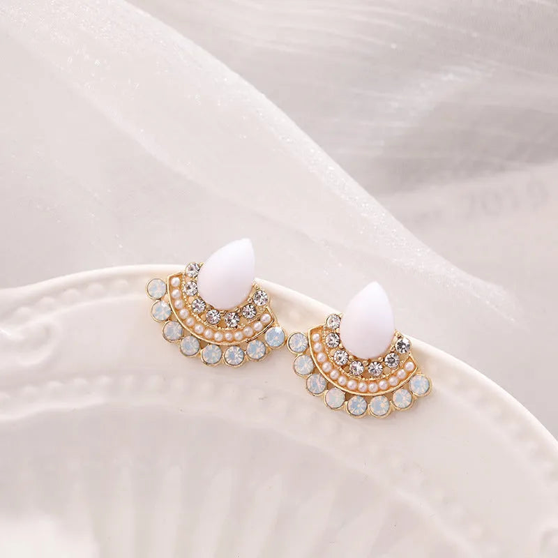 Silver retro fan-shaped stud earrings with rhinestone and opal details on a grey background.