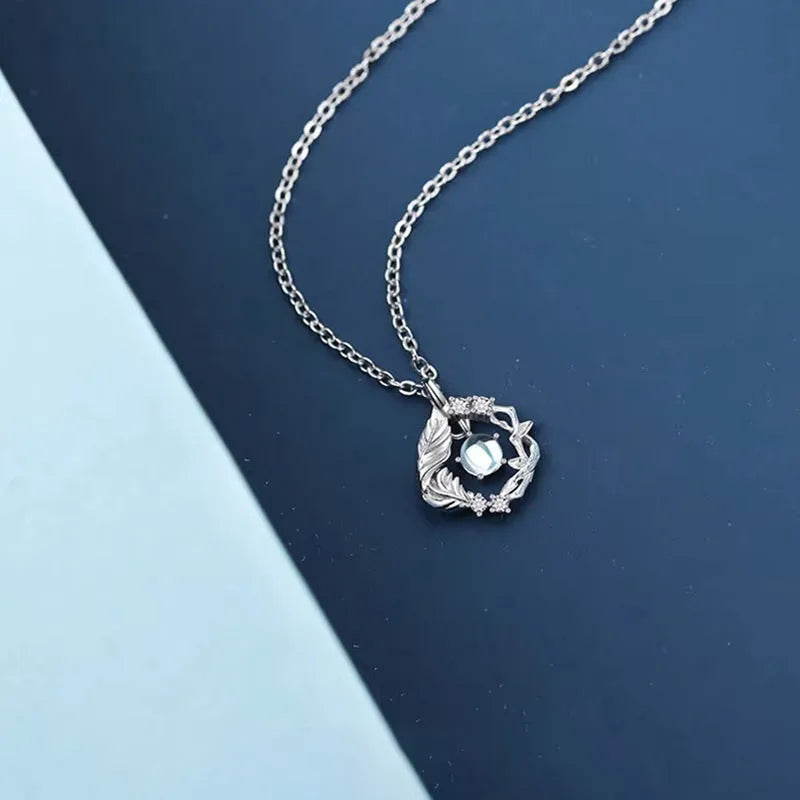 Geometric tree and bird pendant necklace for women with an adjustable chain in a blue eucalyptus colour.