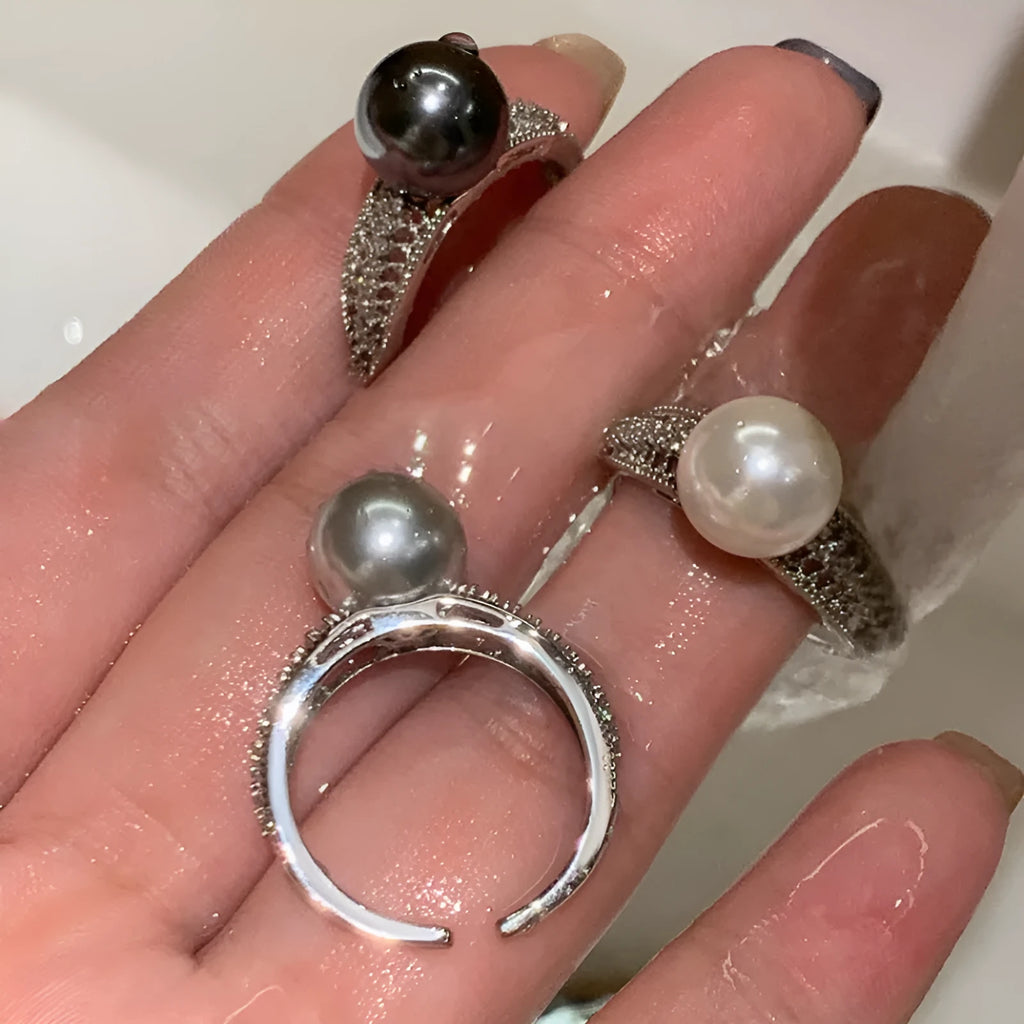 Adjustable open copper ring with a black pearl in a geometric shape for women, shown on an index finger.