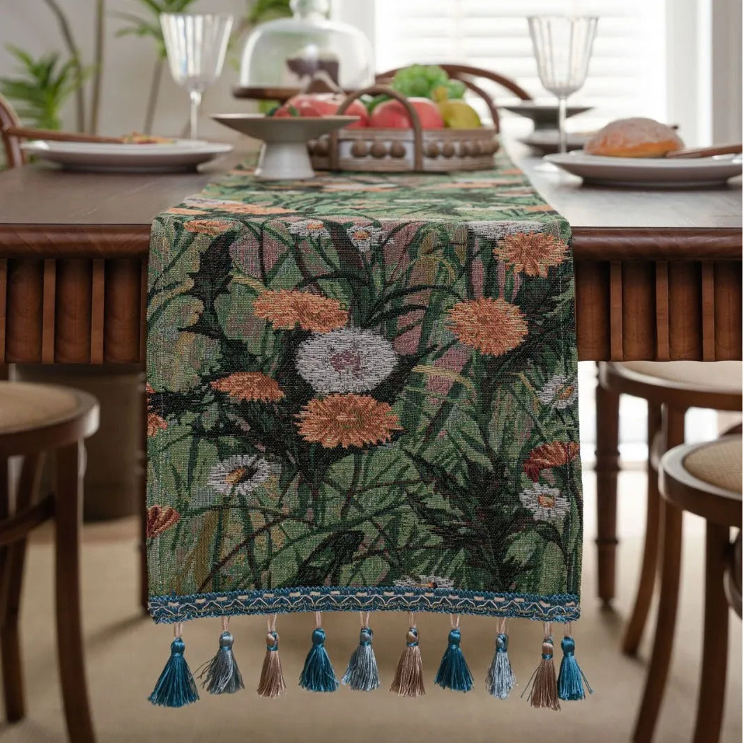 Beige jacquard fabric table runner with floral pattern and long tassels laid flat on a table.