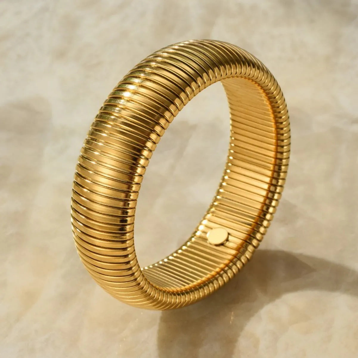 Women's titanium steel bracelet with vertical stripes, shown in gold and silver colours with ring elastic closure.