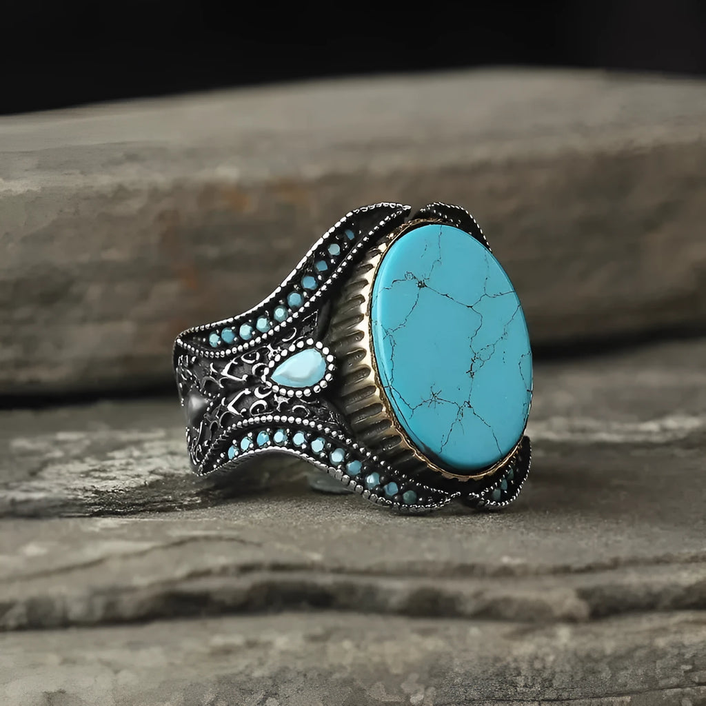Men's round turquoise-style ring in antique silver alloy on a plain background.