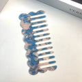 Acetate geometric wave hairdressing comb in pink on white background, 12 cm length