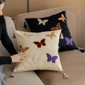 Square decorative cushion with Chinese butterfly embroidery in beige, black, and purple threads.