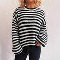 Woman wearing a loose black and white stripe pullover sweater with a round neck and long sleeves.