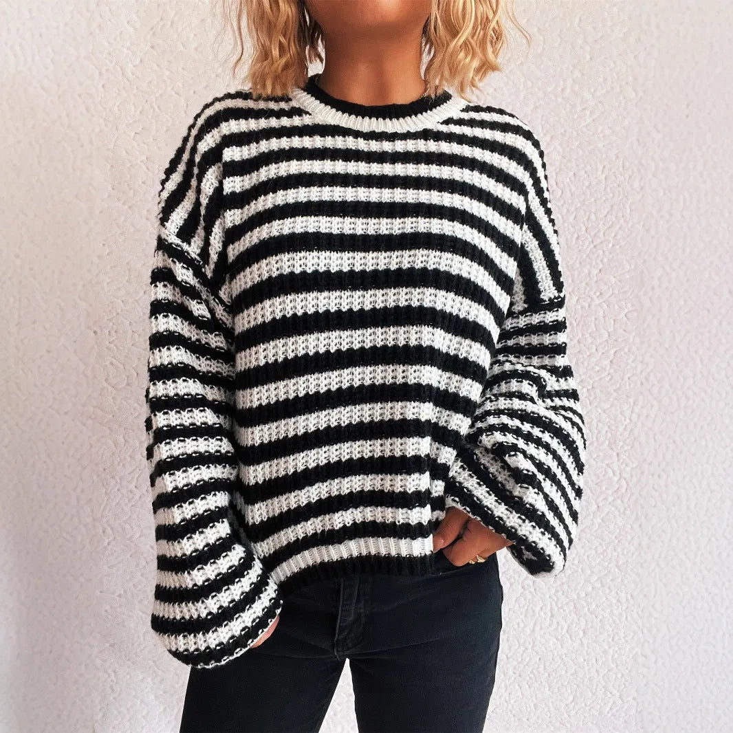 Woman wearing a loose black and white stripe pullover sweater with a round neck and long sleeves.