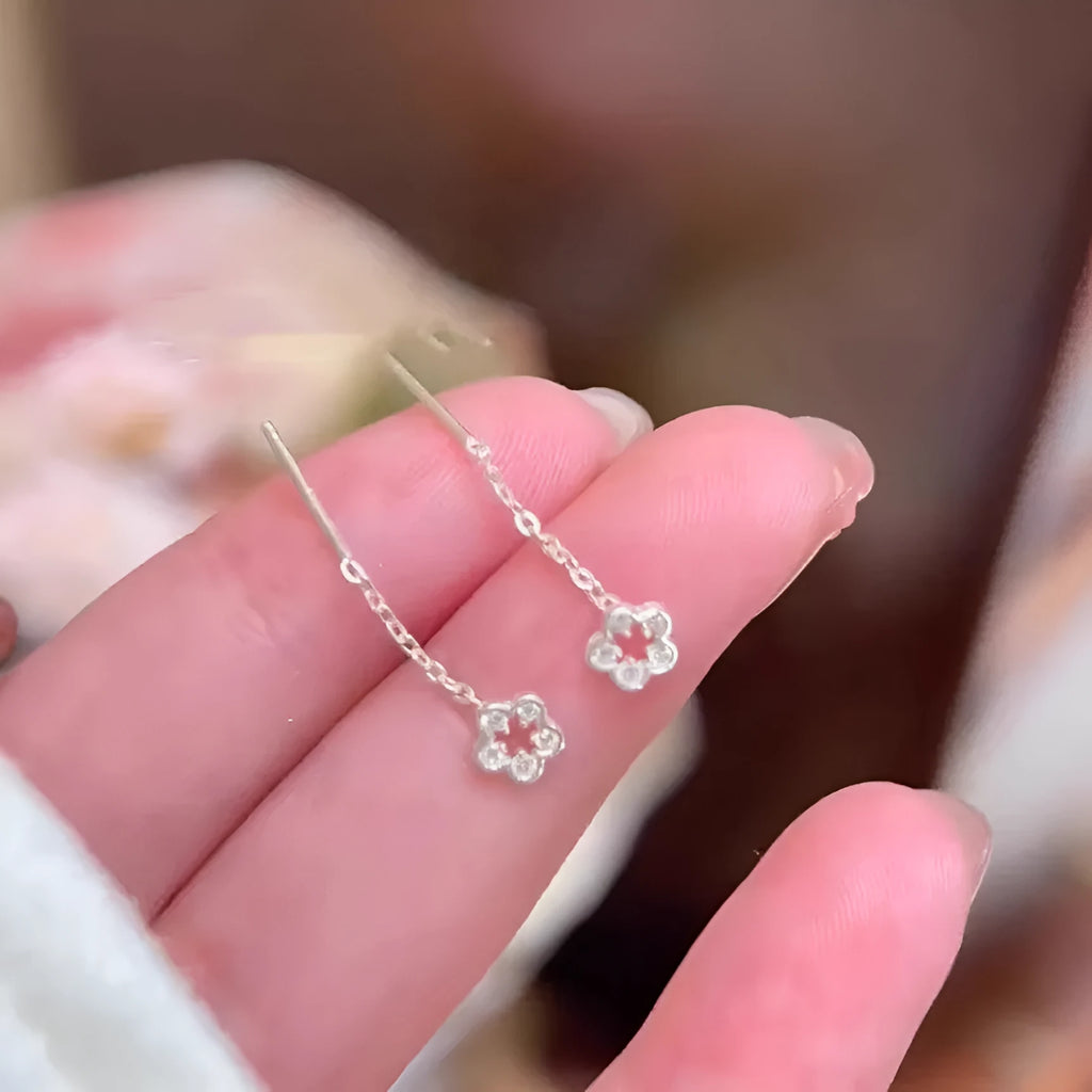 Silver hollow flower hanging earrings with detailed petal design and needle silver construction