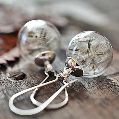 Transparent glass ball earrings with a dandelion seed inside, on a silver French hook.