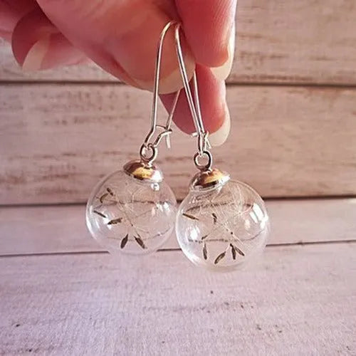 Transparent glass ball earrings with a dandelion seed inside, on a silver French hook.