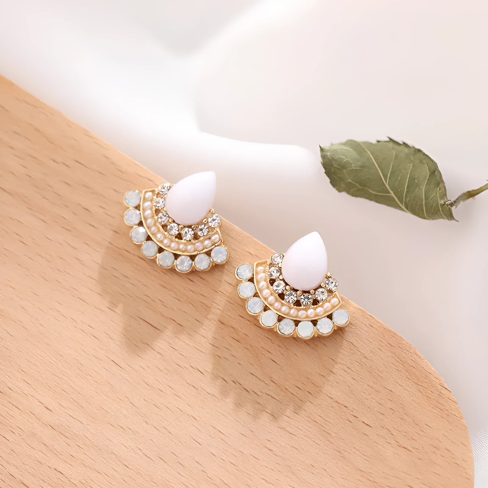 Silver retro fan-shaped stud earrings with rhinestone and opal details on a grey background.