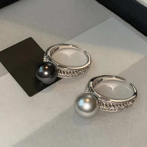 Adjustable open copper ring with a black pearl in a geometric shape for women, shown on an index finger.