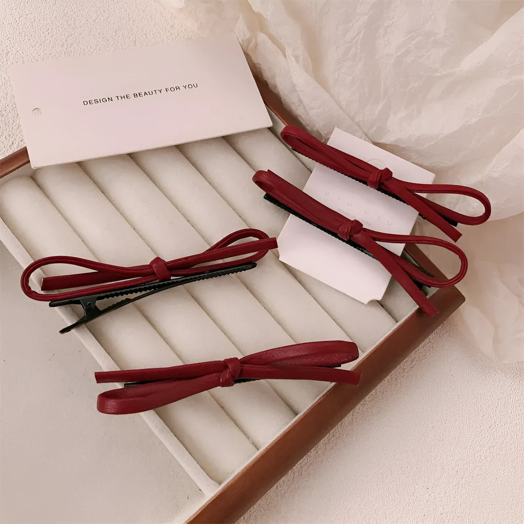 Wine red leather bow design hair barrettes on a white background.
