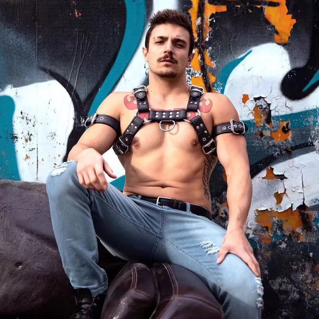Black leather chest muscle bondage strap with metal buckle and rivets laid flat.
