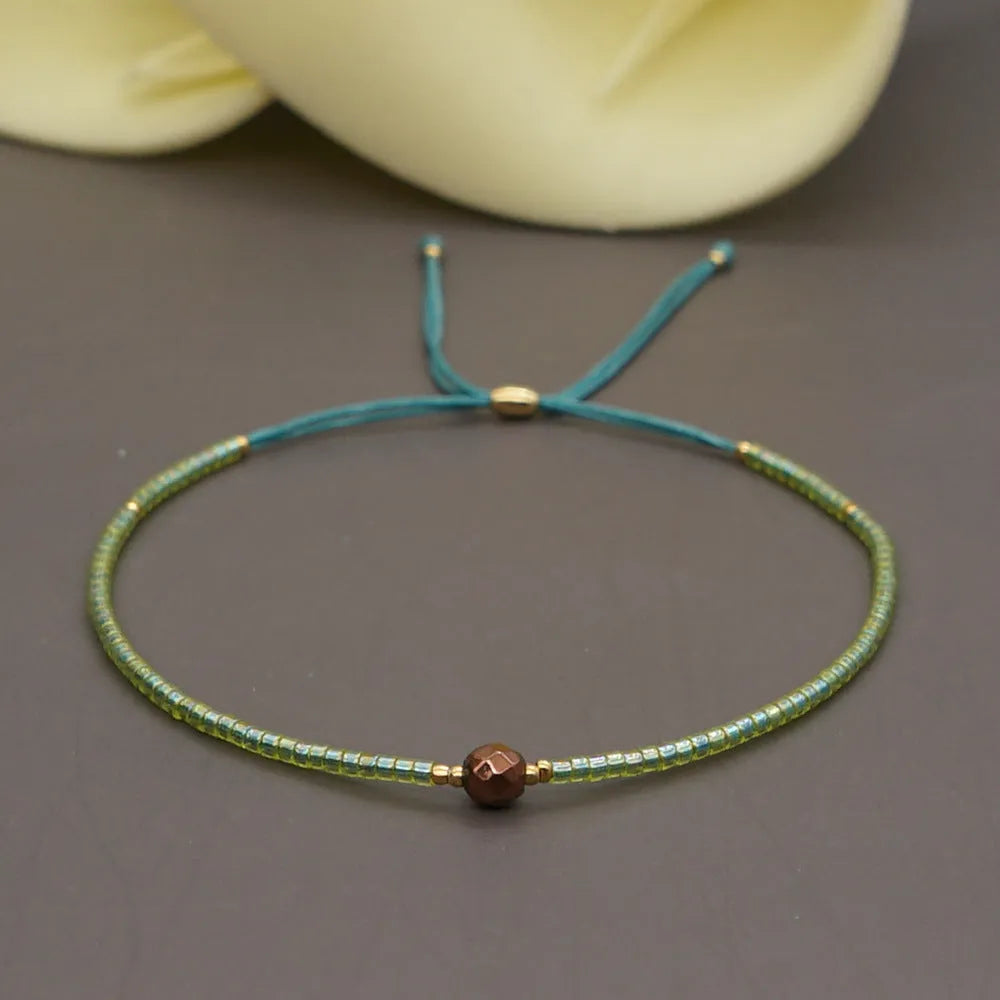 Close-up of a handmade women's bracelet with colourful glass and semi-precious stone geometric beads on a black stretch cord.