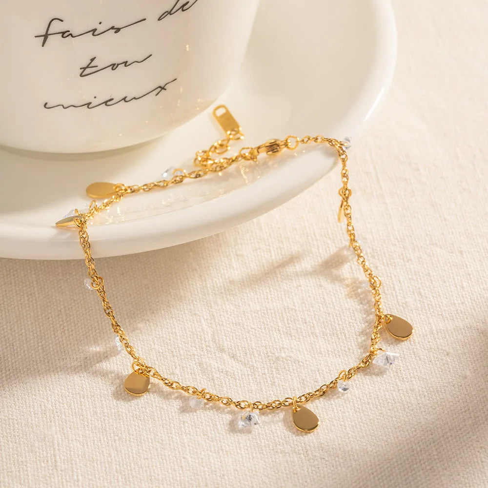 Stainless steel women's anklet with a geometric water drop tassel charm on an ankle.