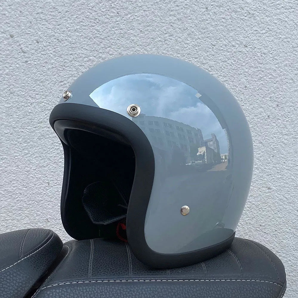 A retro-style grey half helmet for motorcycle riding, shown on a stand.