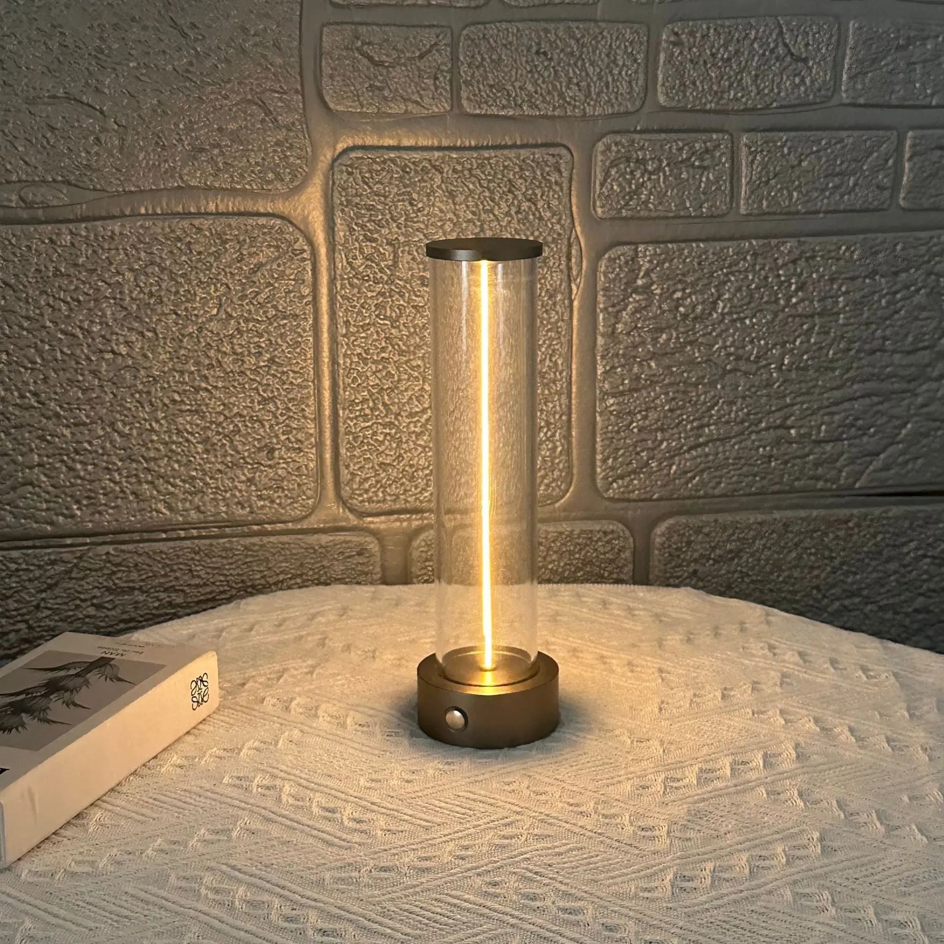 Tall cylindrical frosted glass USB rechargeable LED night light with a magnetic base on a wooden surface.