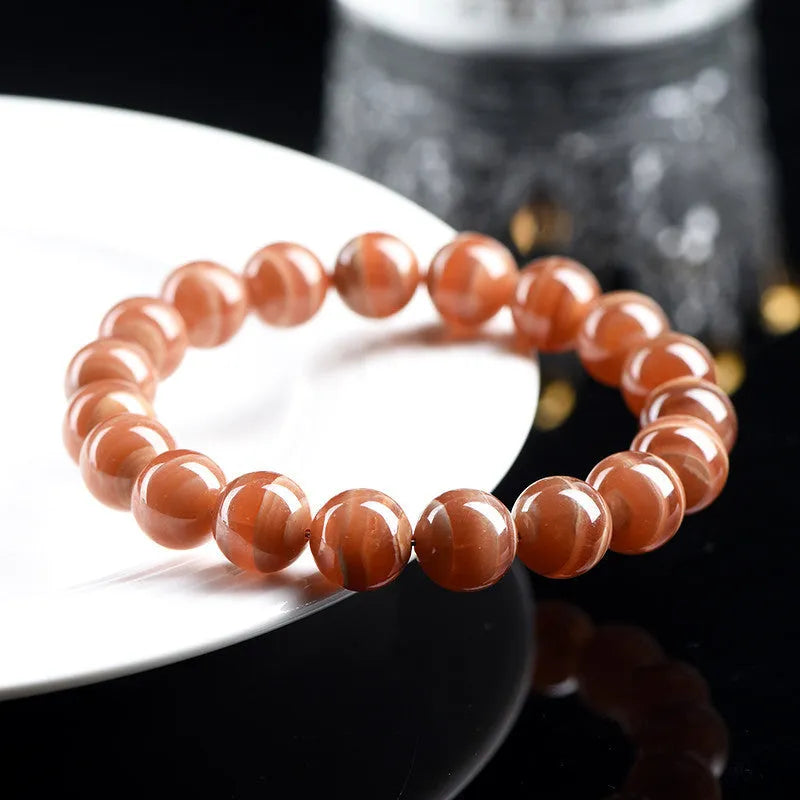 Natural old mine rhodochrosite round bead bracelet with Ruyi detail on a wrist.