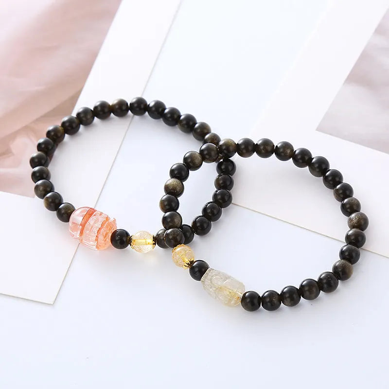 Handmade gold obsidian and red flower bead Pi Xiu bracelet on wrist, ethnic retro style.
