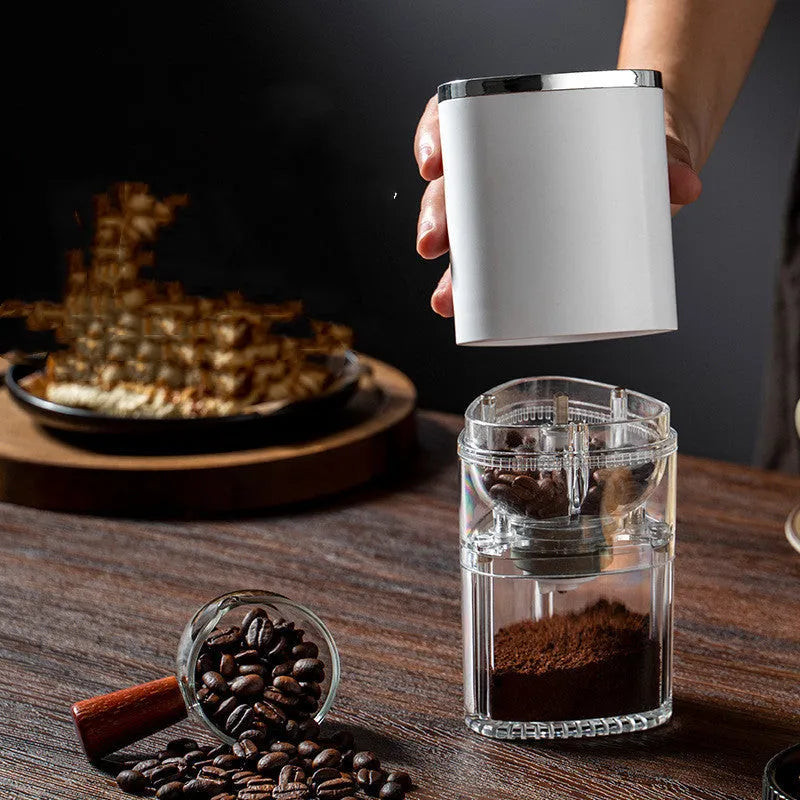 White portable electric coffee grinder with ceramic burr and USB charging cable on a kitchen counter.