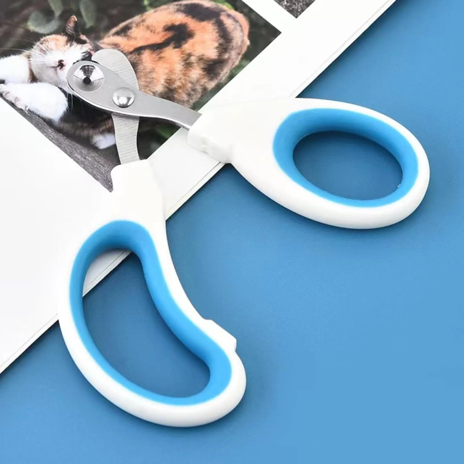 Blue pet nail clippers with circular hole design and cushioned handle on a white background.