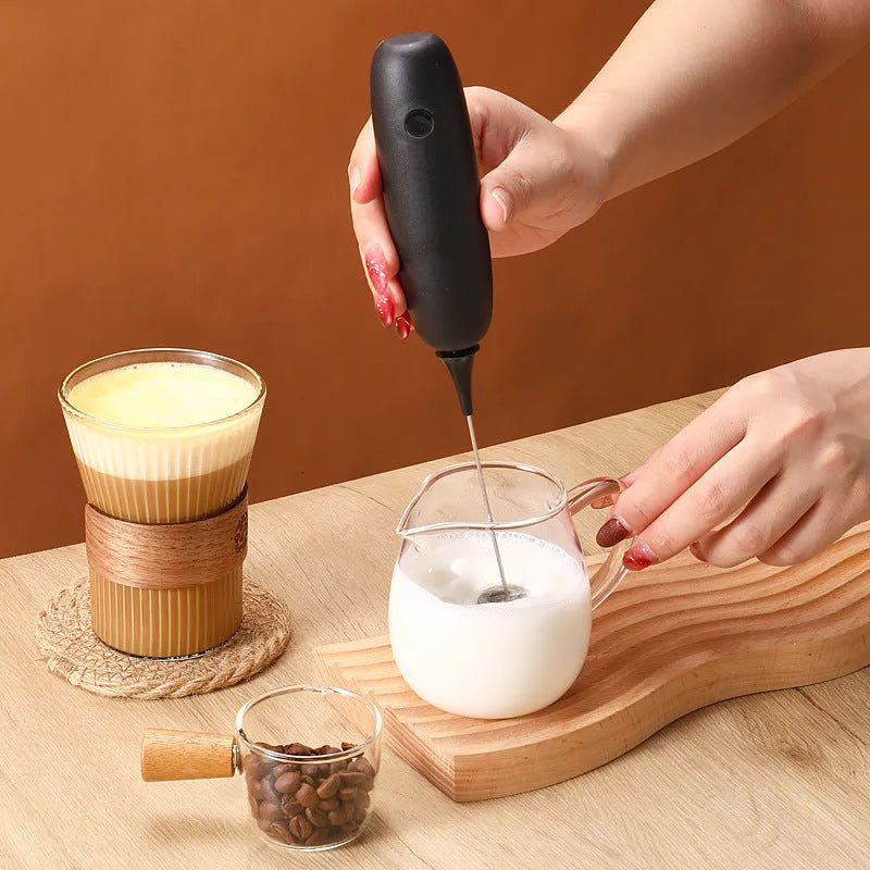 Black and white electric hand-held milk frother and blender for coffee beverages