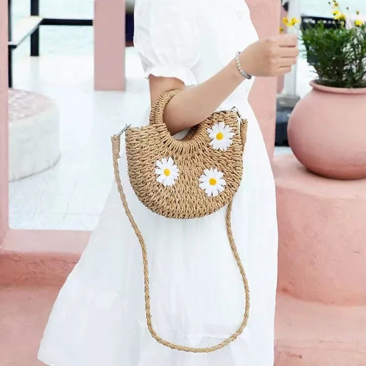 Light brown straw weave crossbody bag with daisy accents and adjustable strap