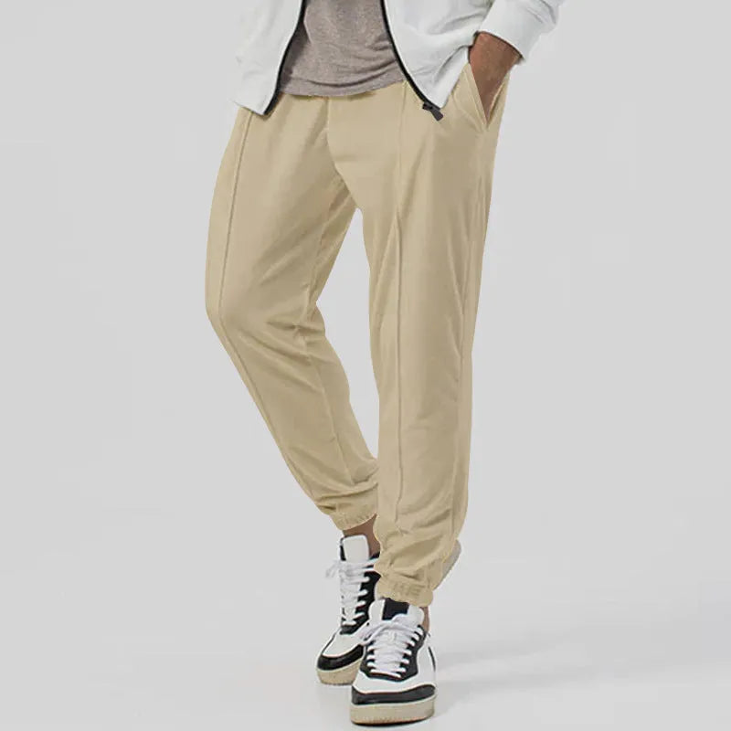 Man wearing grey loose tapered cotton blend track sweatpants with a straight leg.