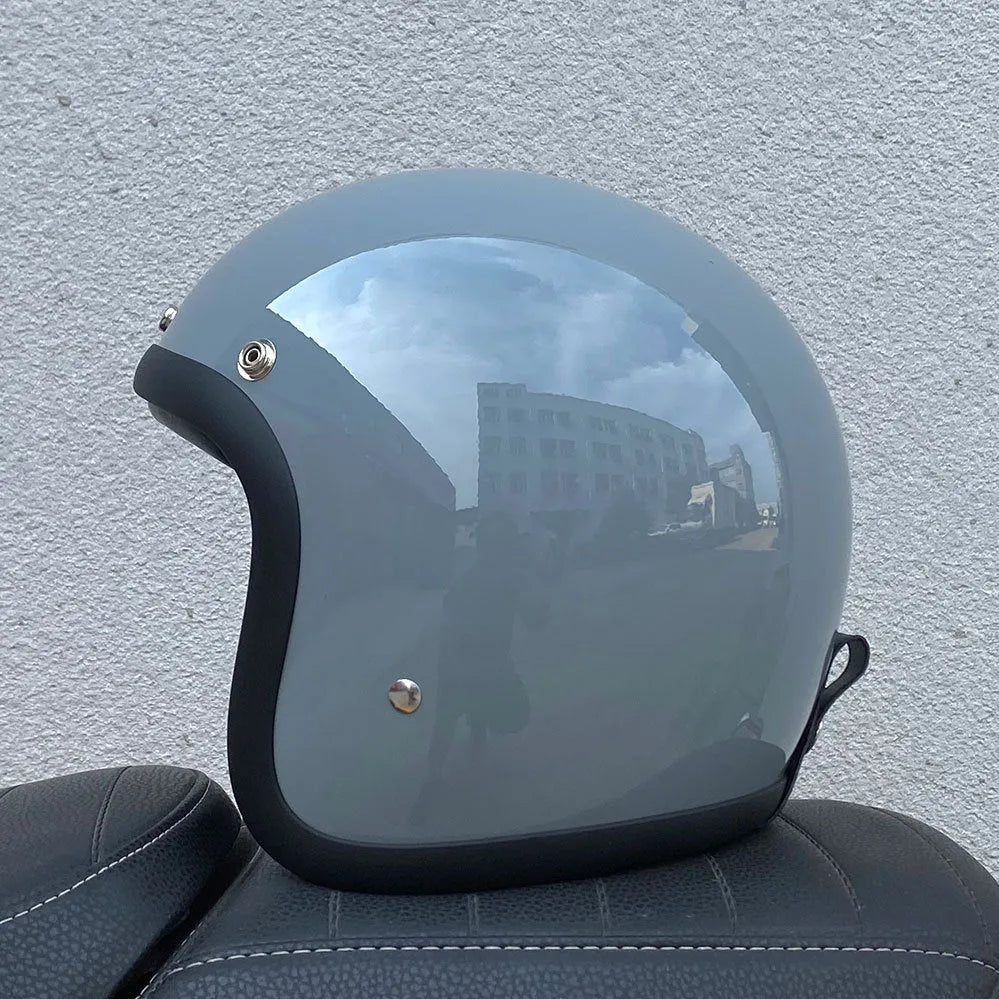 A retro-style grey half helmet for motorcycle riding, shown on a stand.