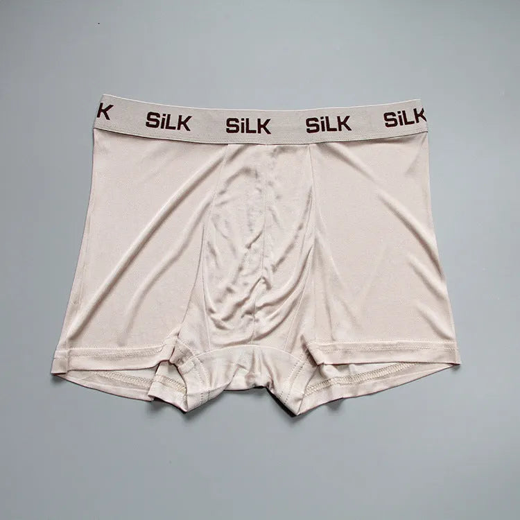 Men's loose-fitting silk shorts in navy blue, shown in a casual setting.