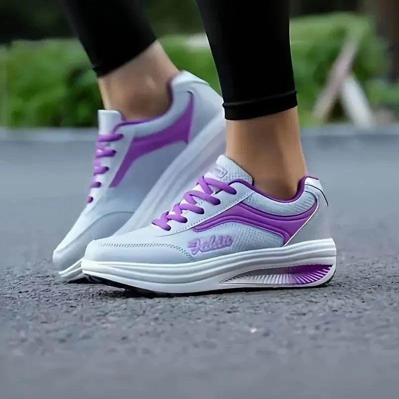 Women's grey powder heelless sports shoes with a middle heel on a plain background.