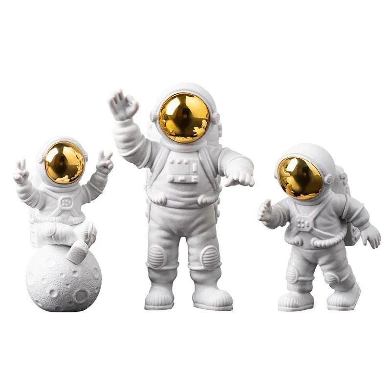 Three resin astronaut figurines for car dashboard decoration, gold finish, placed on dashboard
