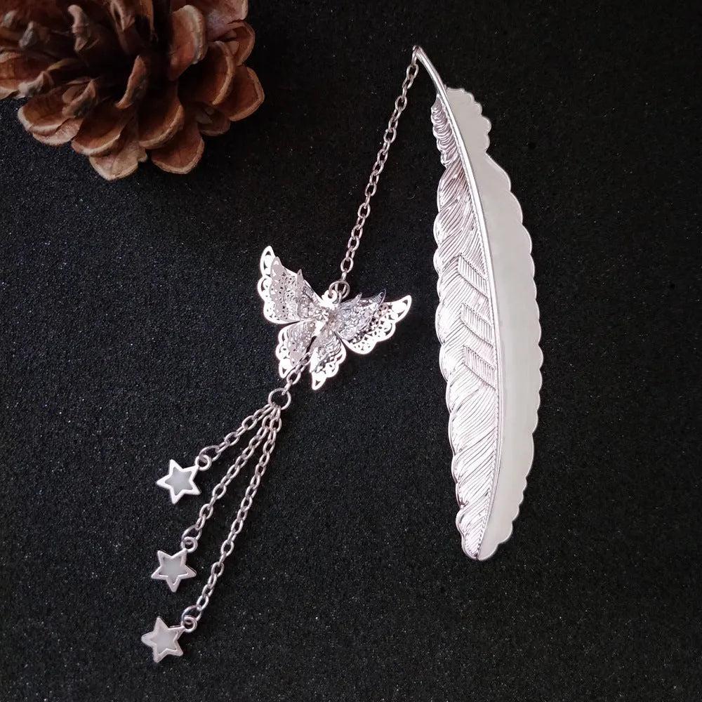 Silver pure copper feather bookmark with glowing luminous butterfly charm on a book.