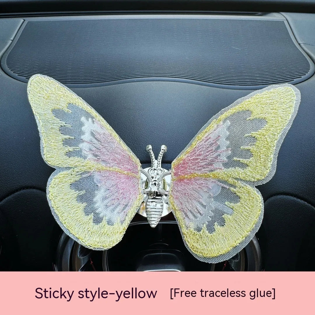 Fabric embroidered butterfly car air vent decoration in multiple colour options on a dashboard.