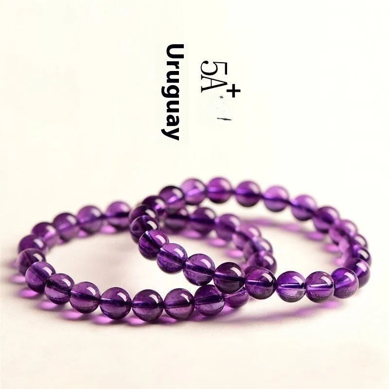 Natural amethyst Uruguay bracelet with scattered polished beads on a white background.