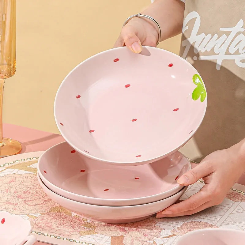 Cute porcelain dinnerware set with strawberry design, instant noodle bowl, twist spoon, and flower-shaped plates on table.
