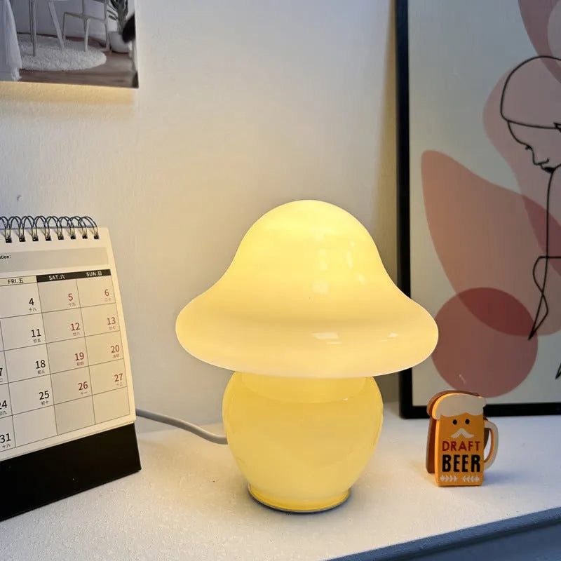 Glass mushroom decorative lamp with three-colour light in orange smooth finish on a wooden table