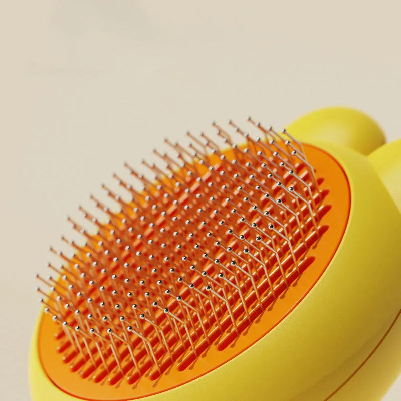 Green self-cleaning pet brush with a metal comb, release button, and comfort-grip handle for grooming cats and dogs.