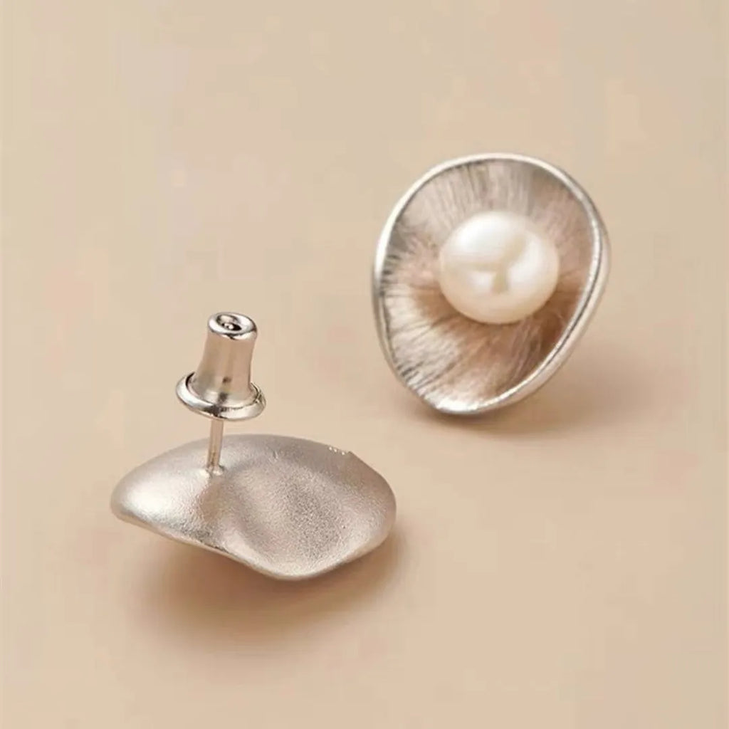 A pair of sterling silver geometric stud earrings featuring a central simulated pearl.