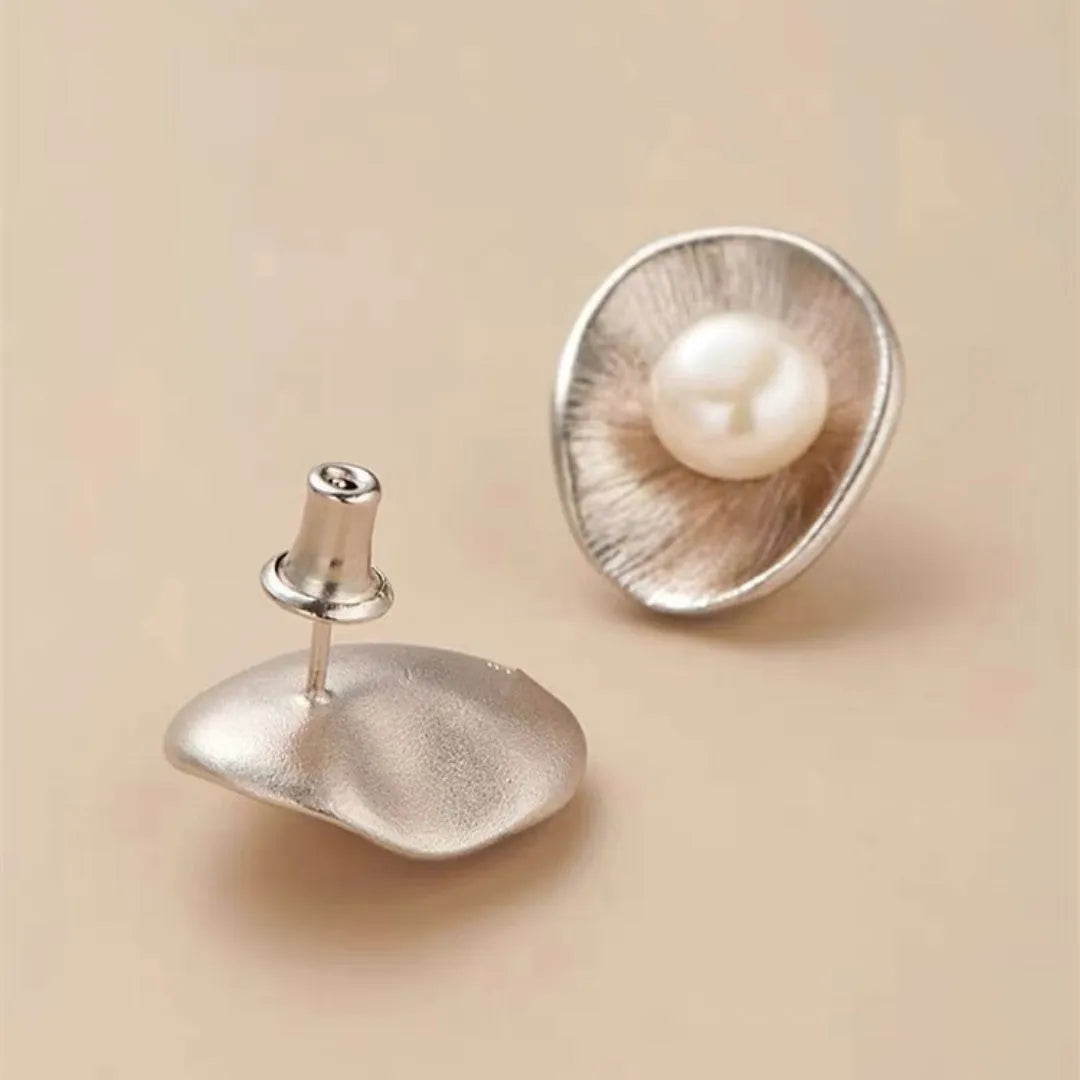 A pair of sterling silver geometric stud earrings featuring a central simulated pearl.