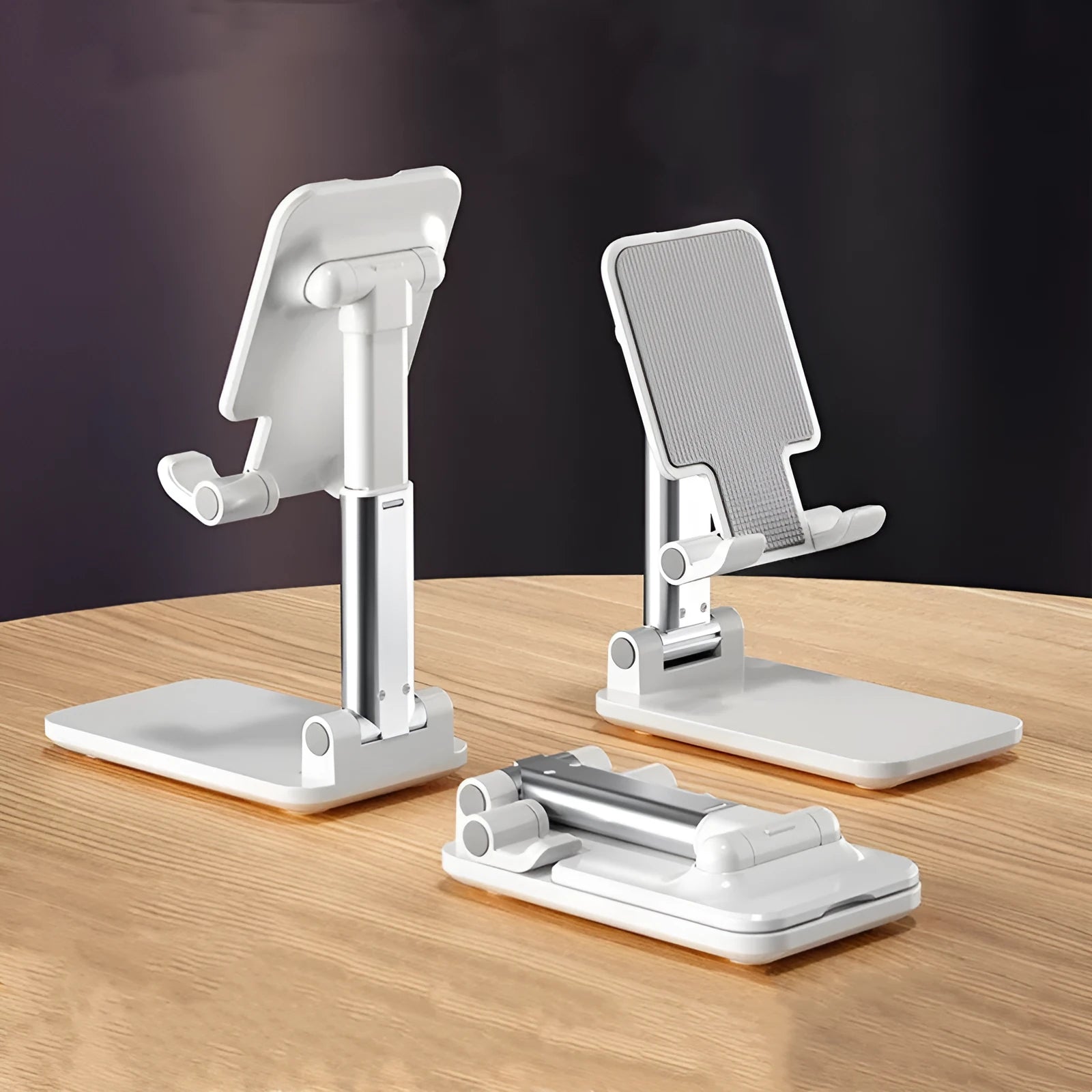 White folding telescopic mobile phone bracket holding a smartphone on a desktop.