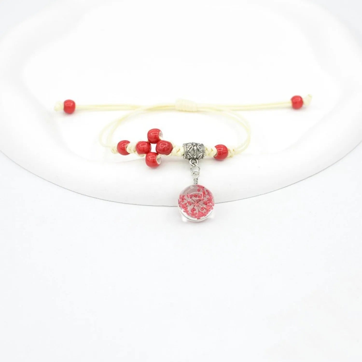 Close-up of a hand-woven glass bracelet with large 1.4cm beads containing real dried flowers in various colours.